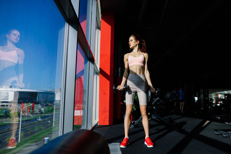 Athletic girl in sportswear performs exercises with a barbell, dumbbells. Fitness, workout, healthy...