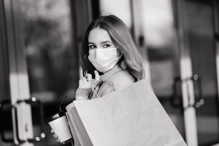 Young female wearing mask for prevent virus with shopping bags on narrow street in Europe.