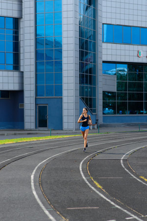 Outdoor shot of young woman athlete running on racetrack. Professional sportswoman during running...