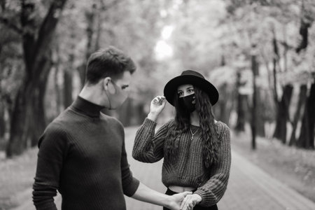 Young couple wearing masks together in forest, park