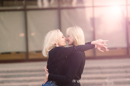 Two young females walking smiling embracing and kissing outdoorの写真素材