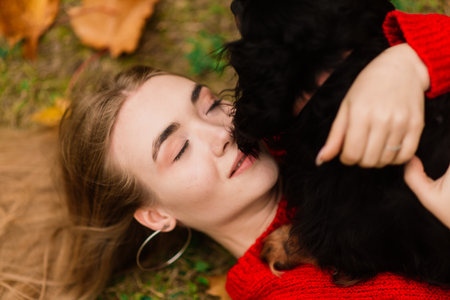 Happy woman holding her little dog in arms, autumn parkの写真素材