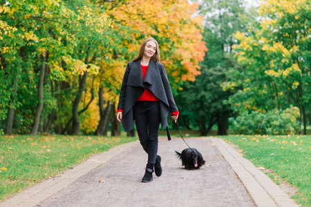 Young attractive woman holding her dachshund dog in her arms outdoors in sunrise in park at autumn timeの写真素材