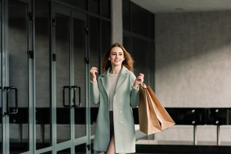 Portrait of cheerful young lady holding shopping bags outdoorの写真素材