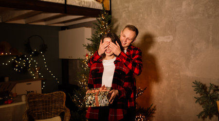 Young guy kissing her lovely girlfriend feeling happiness while celebrating winter holidays...