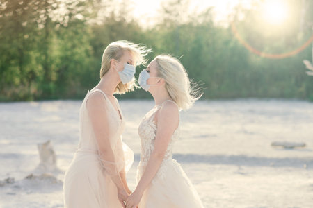 Lesbian couple wedding on white sand, wear masks to prevent epidemic COVID-19