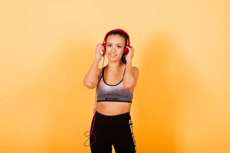 Minsk, Belarus - 01.22.2021. Strength and motivation. Full length of young and slim african woman in sports clothing exercising in studio against yellow backgroundのeditorial素材