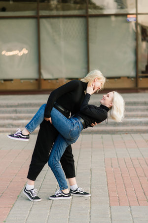 Two young females walking smiling embracing and kissing outdoorの写真素材