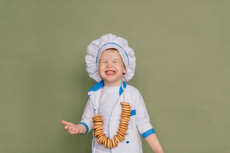 Portrait of a little boy cook holding pan at the kitchen. Different occupations. Isolated over white...