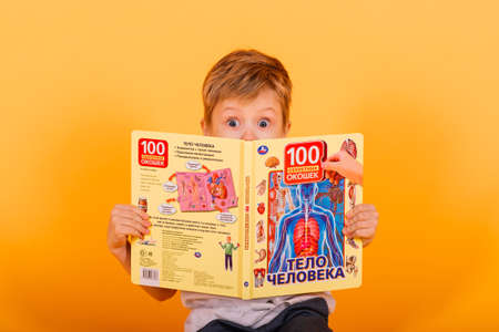 Minsk, Belarus - 01.09.2021. Portrait of little schoolboy with book on yellow background, studioのeditorial素材
