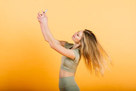 Portrait of young sporty woman smiling while sitting and training isolated on grey background