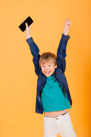 The little boy phones on yellow backgroundの写真素材