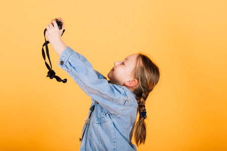 A little cute girl making photo on a yellow background.