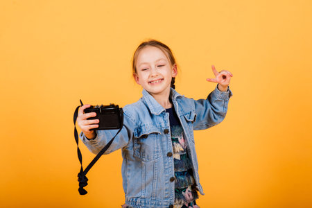 A little cute girl making photo on a yellow background.