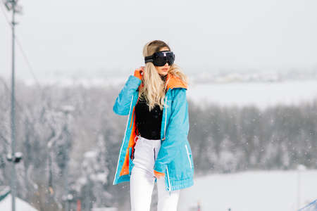 Young sporty smiling woman in winter with snowboard, glassesの写真素材