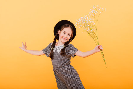 Funny child girl smiling with bouquet of flowers on coloured backgroundの写真素材