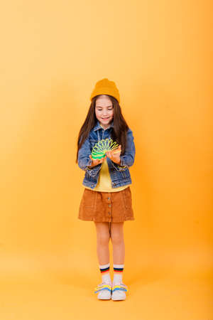 Minsk, Belarus - 02.18.2021. Beautiful young girl playing with a rainbow slinky, a toy of her childhood on a studio backgroundのeditorial素材