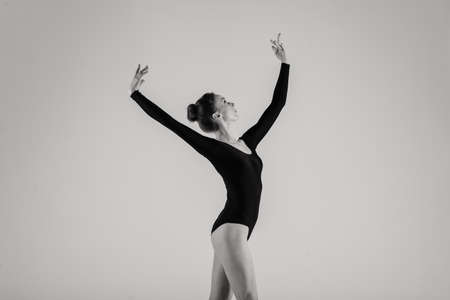 Portrait of Sensual professional caucasian ballet dancer in body suit and pointes shoes posing on floor on white.の写真素材