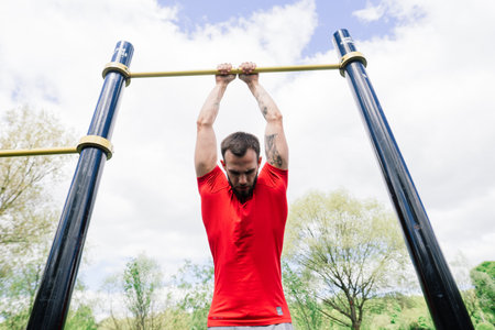 Minsk, Belarus - 05.23.2020. Caucasian sportsman pulling up wide grip hand on crossbar during street...
