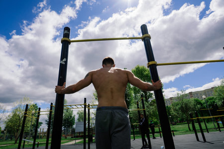 Minsk, Belarus - 05.23.2020. Caucasian sportsman pulling up wide grip hand on crossbar during street...