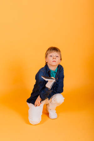 Smart ginger-haired young schoolboy with notebook isolated over yellow background, studioの写真素材