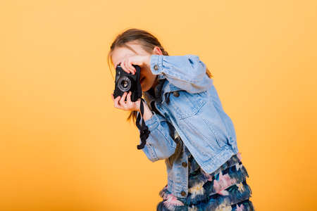 A little cute girl making photo on a yellow background.の写真素材