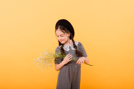 Funny child girl smiling with bouquet of flowers on coloured backgroundの写真素材