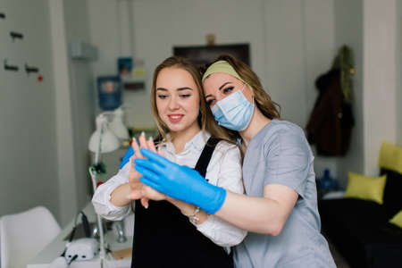 Smiling woman at beauty salon has a manicure from manicure master. Master is using nail file.の写真素材