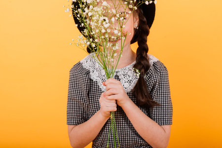 Portrait of cute little girl with flower bouquet in the studio on yellow background. Congratulation,...