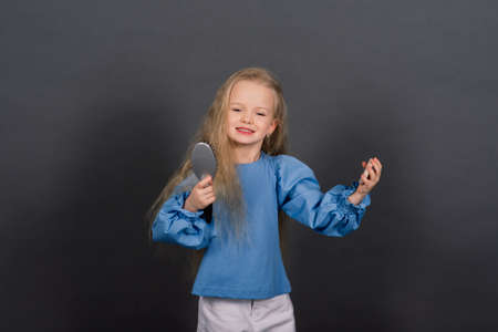 Little girl brushes her tangled hair after a shower, studio shotの写真素材