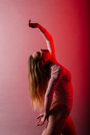 Slender female on coloured background of neon color posing in a bodysuitの写真素材