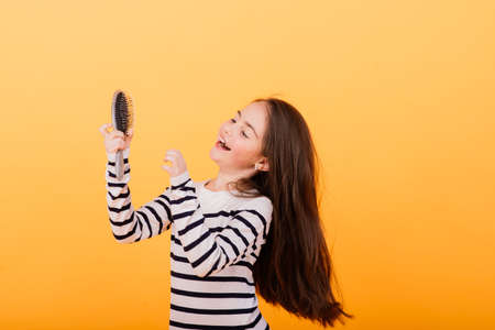 Little girl singing using hairbrush as microphoneの写真素材