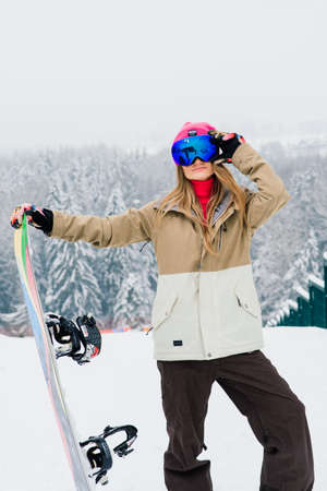 Minsk, Belarus - 01.22.2021. Young sporty smiling woman in winter with snowboard, glassesのeditorial素材