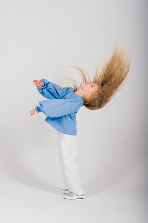 Portrait smiling child girl with flying blond hair, studioの写真素材