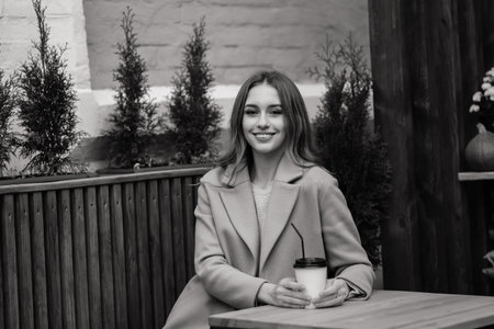 Very beautiful young woman, sit in Cafe and drink coffee or tea with croissant, street front view