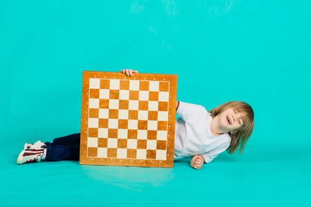 Cute kid holding a game of chess in his arms, studio shotの写真素材