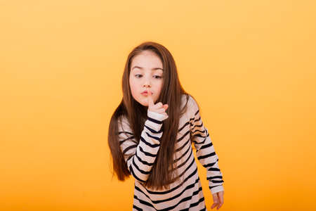 Portrait of a beautiful and confident girl showing emotions isolated on yellow, studioの写真素材