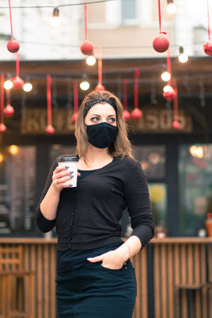 A sweet female of caucasian appearance in black face mask, sits and works in an Internet cafe.の写真素材