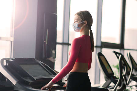Woman wearing face mask exercise workout in gym during corona virus pandermic, covidの写真素材