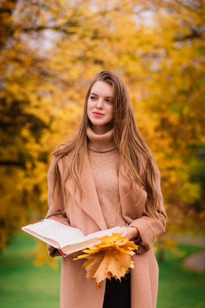 Beautiful woman spending time in a park during autumn seasonの写真素材