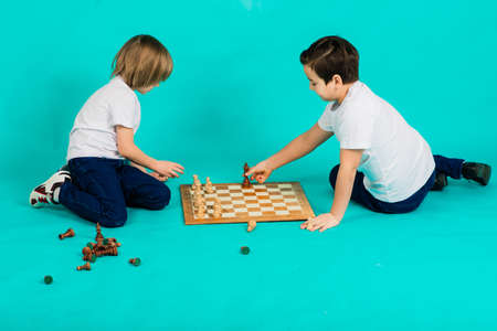 Two serious boy playing chess in studio, blue backgroundの写真素材