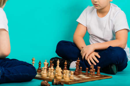 Two serious boy playing chess in studio, blue backgroundの写真素材