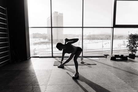 Beautiful muscular woman doing exercise with gymnastic stick in a gym. Swedish wall in backgroundの写真素材