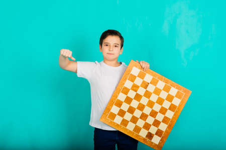 Cute kid holding a game of chess in his arms, studio shotの写真素材