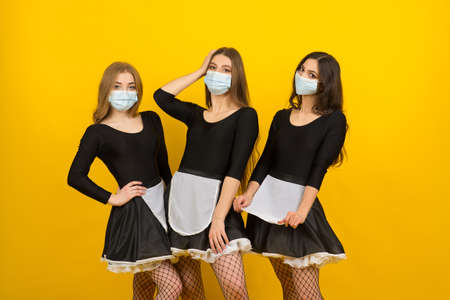 Beautiful sexy women in maid clothes posing in studio in covid protective maskの写真素材
