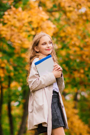 Portrait of a cute schoolgirl with interesting book in natural environmentの写真素材