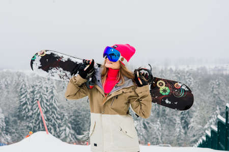 Minsk, Belarus - 02.21.2021. Woman snowboarder standing with snowboard. Portrait of cheerful female at top of ski slopeのeditorial素材