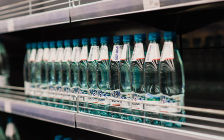 Minsk, Belarus - 03.29.2021. Few drinking mineral water bottles on shelf left in department store, lack of a goodsのeditorial素材