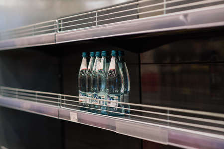 Minsk, Belarus - 03.29.2021. Few drinking mineral water bottles on shelf left in department store, lack of a goodsのeditorial素材