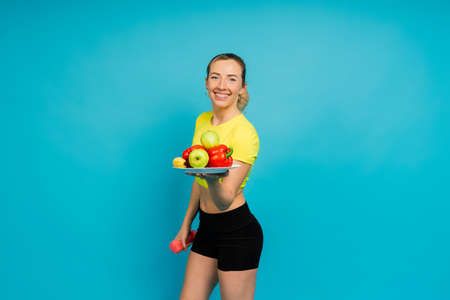 Studio shot of young fitness woman in a sports clothing holding green apple, fruits, vegetables.の写真素材